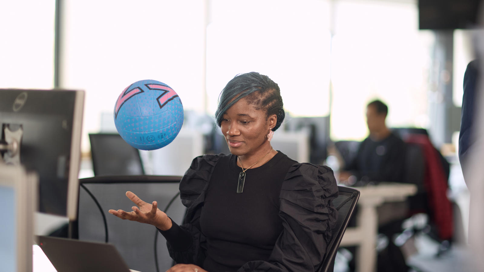 a person sitting at a desk with a ball in her hand